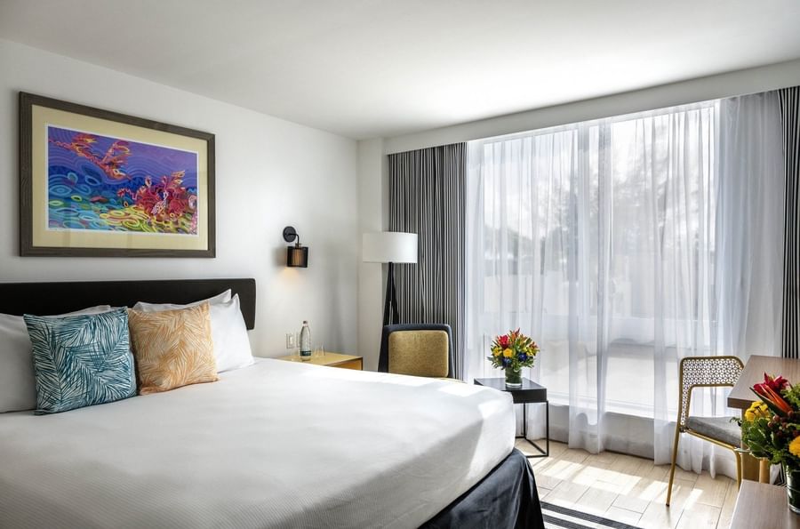King bed with floral pillows by a striped rug under a artwork in Island View Accessible at Warwick Paradise Island Bahamas