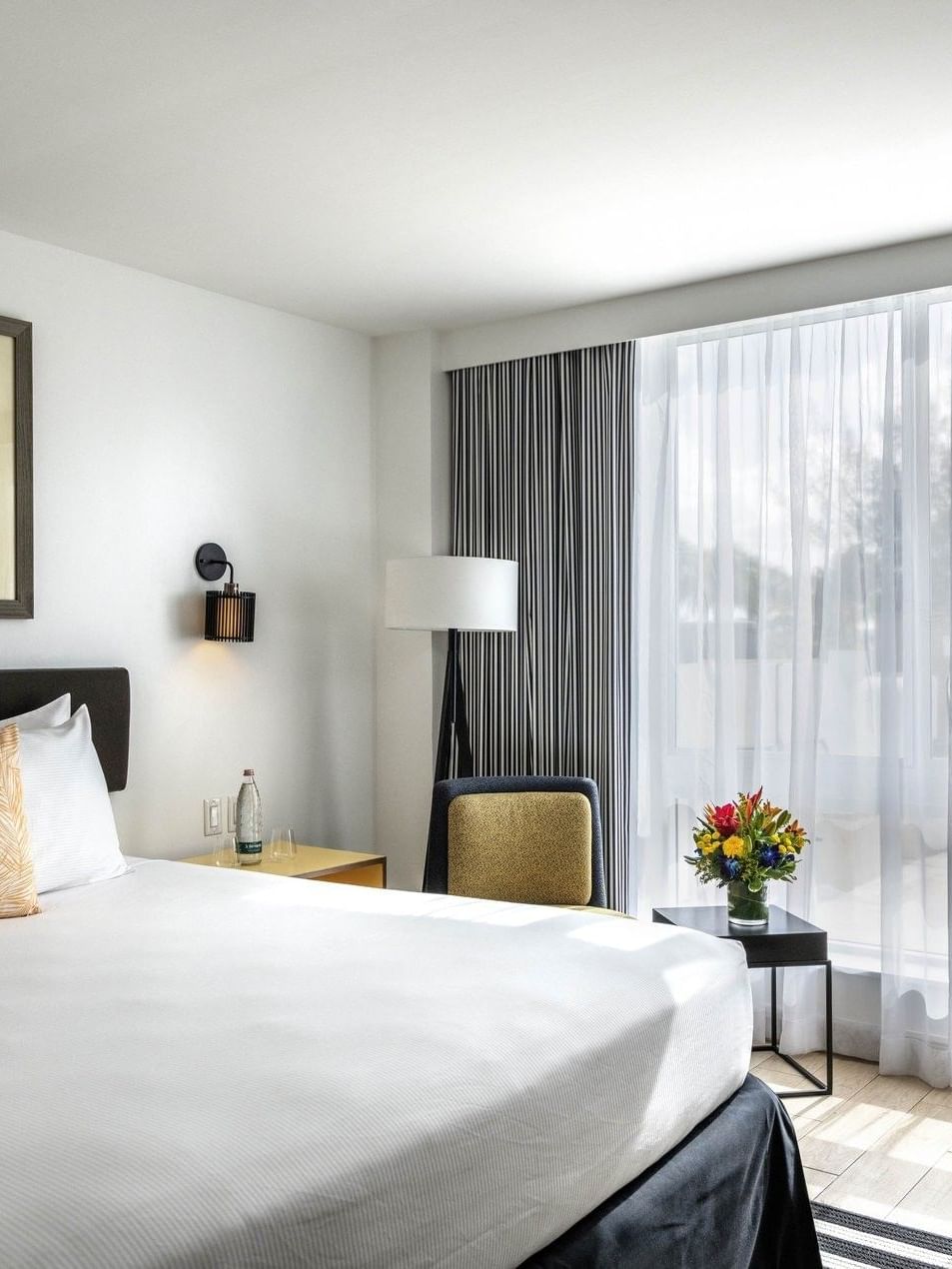 White bed by a floor lamp and armchair under a colorful painting in Island View at Warwick Paradise Island Bahamas