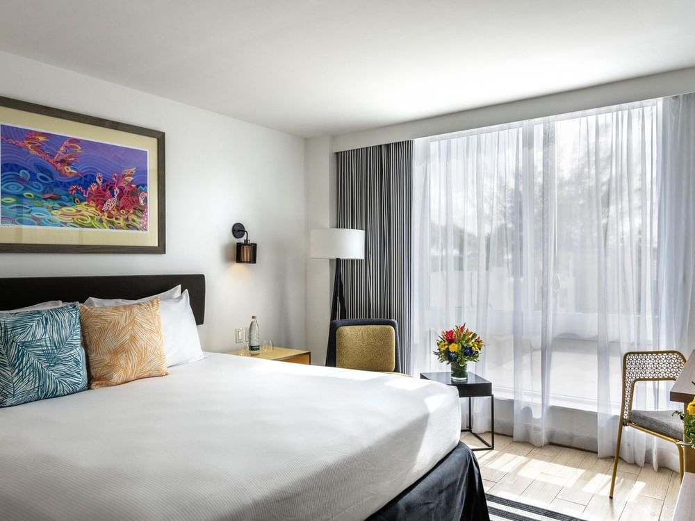 White bed by a floor lamp and armchair under a colorful painting in Island View at Warwick Paradise Island Bahamas