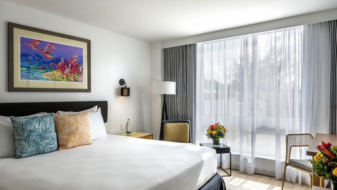 White bed by a floor lamp and chair under a colorful painting in Island View Accessible at Warwick Paradise Island Bahamas