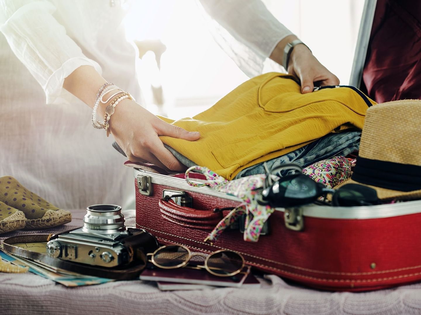 Close-up of a woman packing a suitcase at La Galerie Hotel