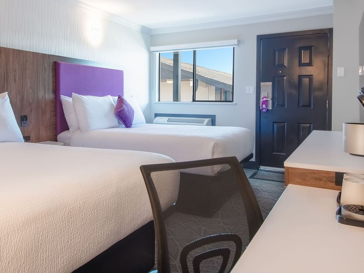 Hotel guestroom with two queen beds, flat screen TV, work desk and chair