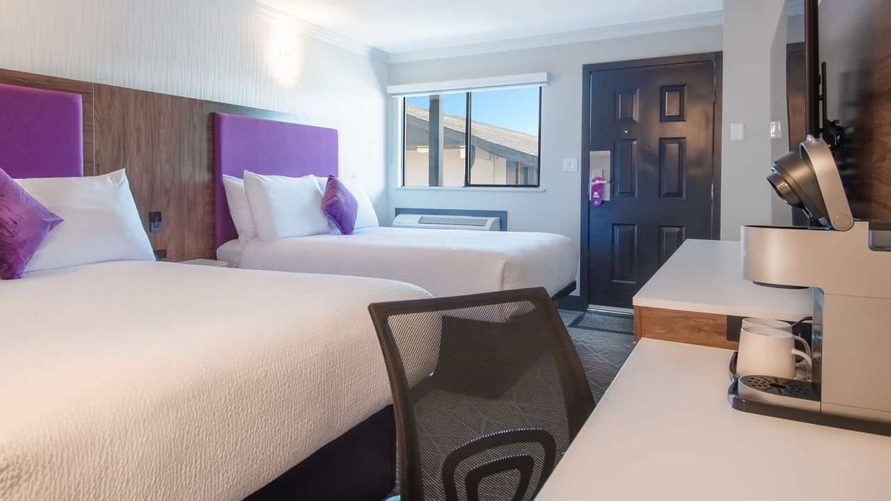 Hotel guestroom with two queen beds, flat screen TV, work desk and chair