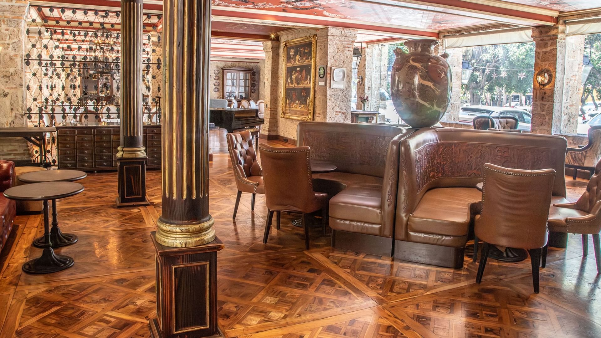 Tierra Mia restaurant interior with leather seating, decorative columns, and herringbone wood floors at Quinta Real Guadalajara