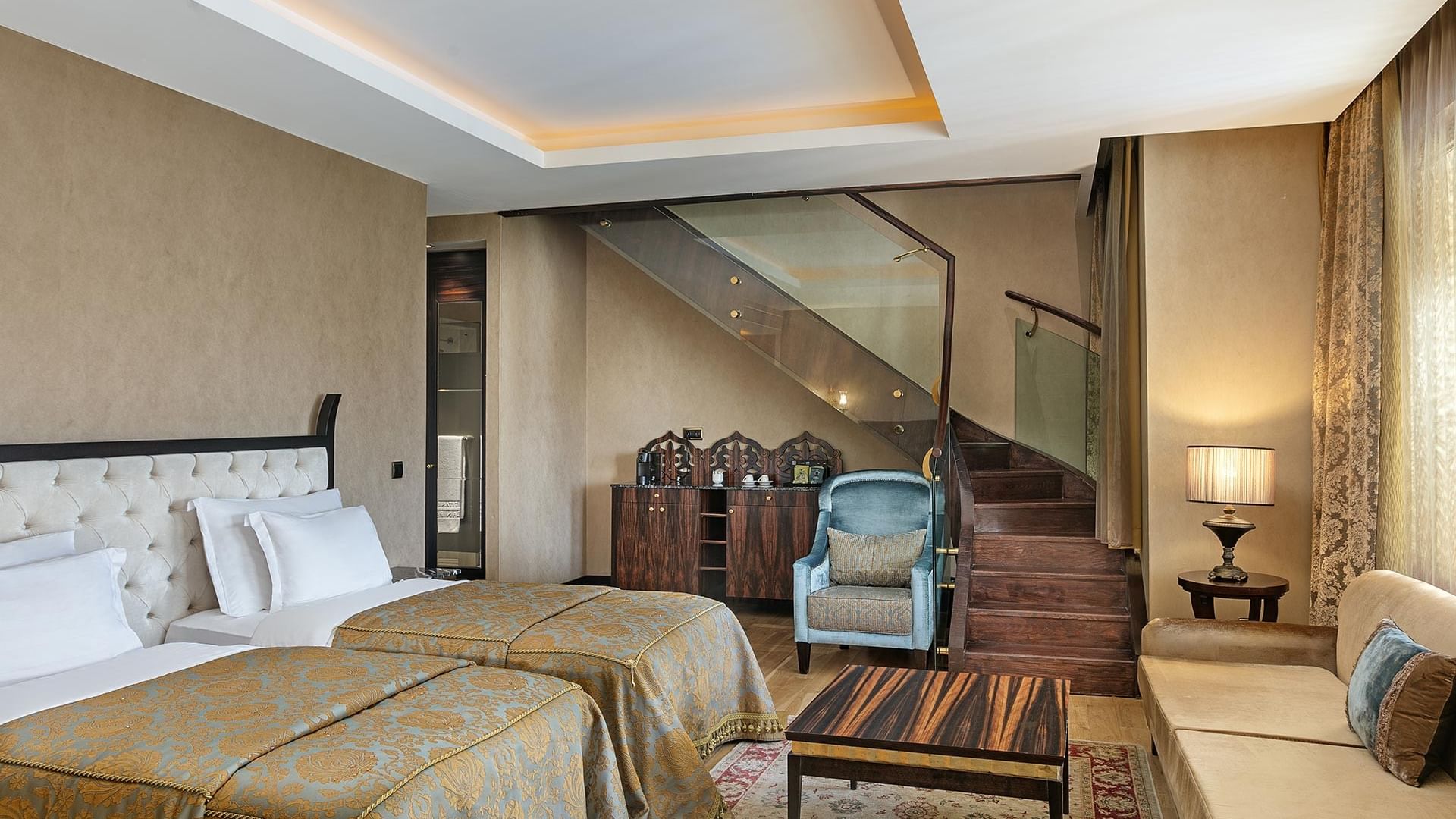 Гранд двухуровневый люкс в отеле Titanic Mardan Palace с двумя кроватями, диваном, стульями и стеклянной лестницей на верхний этаж