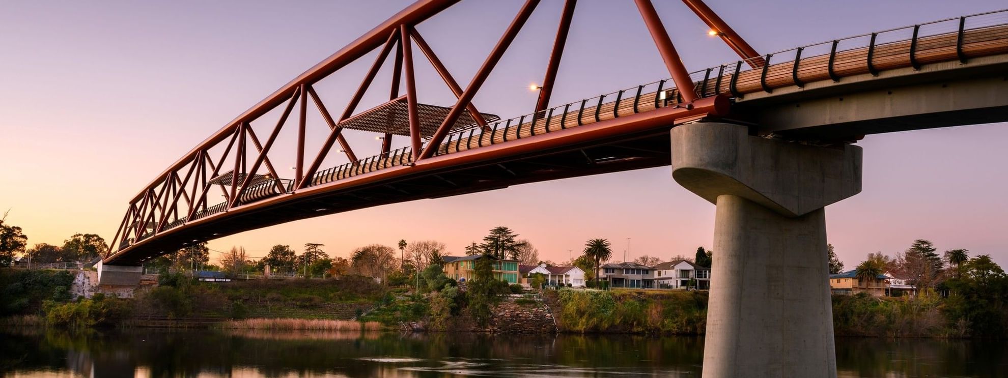 Scenic view of Nepean Great River Walk bridge over a calm river at sunset.