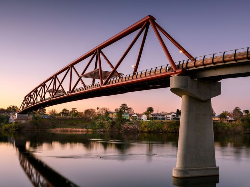 Scenic view of Nepean Great River Walk bridge over a calm river at sunset.
