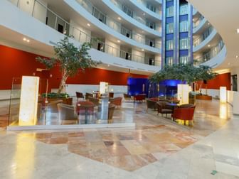 Spacious indoor atrium featuring multi-level balconies, trees, and cozy seating areas at Camino Real Pachuca