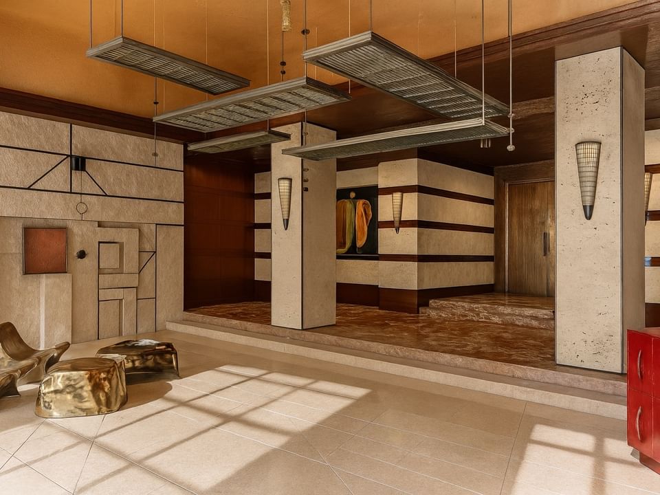Stone wall art and decorative pillars leading to wooden double doors in the Lobby Lounge at Thompson Rome