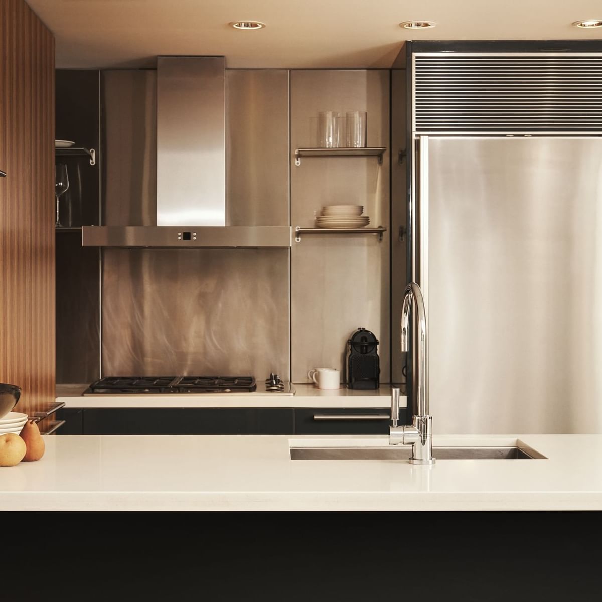 Modern kitchen with stainless steel appliances, white countertops, and a sink with a faucet.