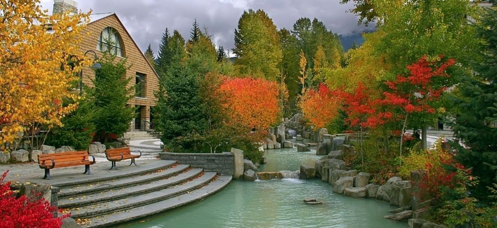 Scenic pond and fall foliage in Whistler Village with colorful trees and mountain backdrop, a top autumn travel destination in British Columbia.
