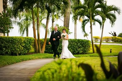 Father walking bride across landscape.