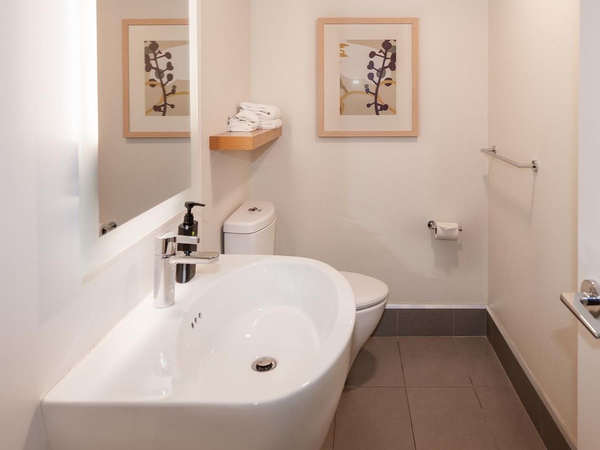 Modern white bathroom with a large sink, toilet, and shower in Coast Premium King One Bedroom Suite at Coast Bastion Hotel Nanaimo.