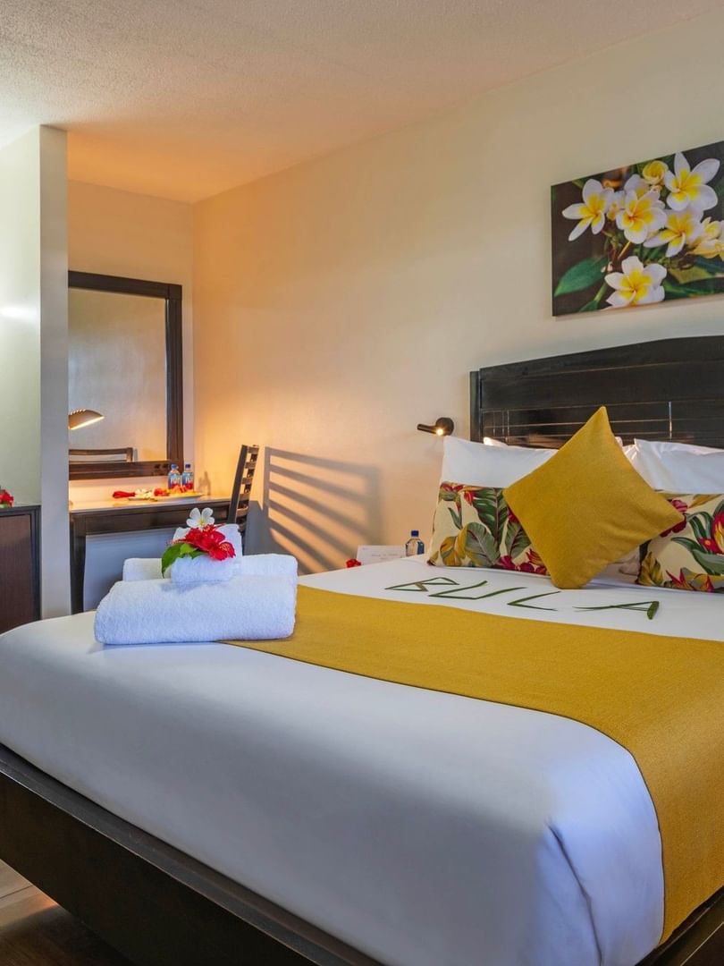 Standard Room with a large bed, tropical decor, and wooden floors at Tokatoka Resort - Fiji International Airport in Nadi