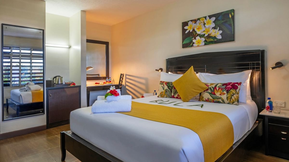 Standard Room with a large bed, tropical decor, and wooden floors at Tokatoka Resort - Fiji International Airport in Nadi.