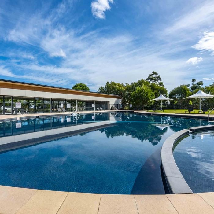 Outdoor pool with sun loungers and white parasols at Mercure Kooindah Waters