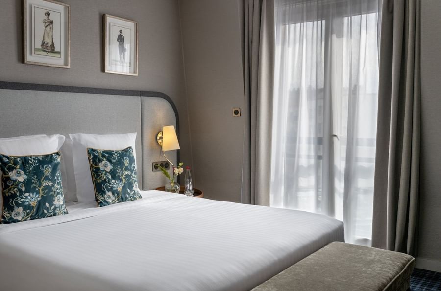 Ottoman and nightstands by the cozy bed with cushioned headboard in the Privilege Suite at Warwick Reine Astrid - Lyon