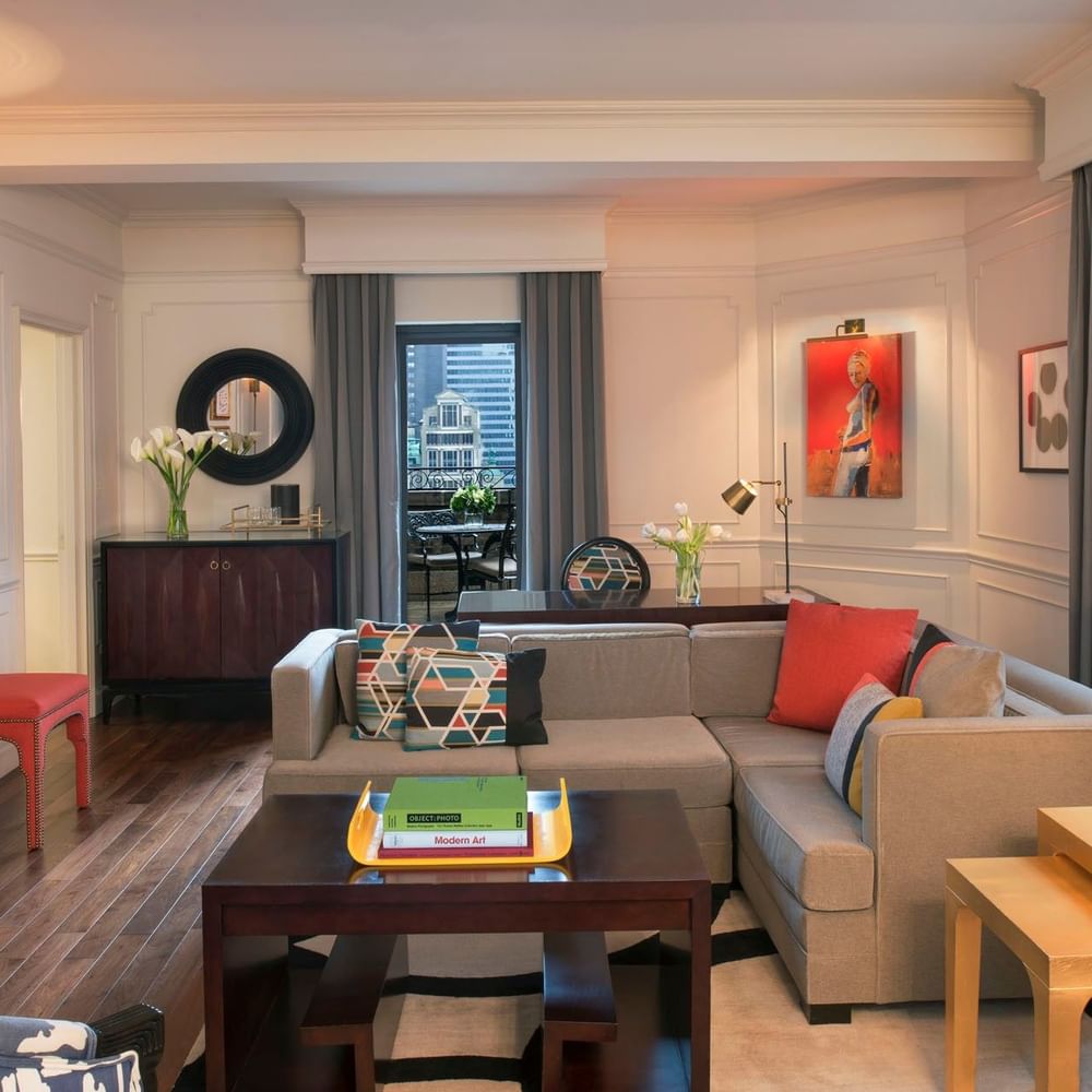 Living area with a grey sectional sofa & colorful pillows, and vibrant red artwork in Modern Art Suite at Warwick New York