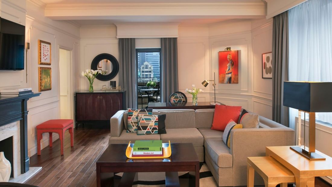 Living area with a grey sectional sofa & colorful pillows, and vibrant red artwork in Modern Art Suite at Warwick New York
