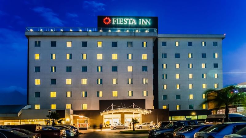 Luxurious room at Fiesta Americana Travelty with ornate wooden Furniture, red carpet, green walls, and elegant seating area