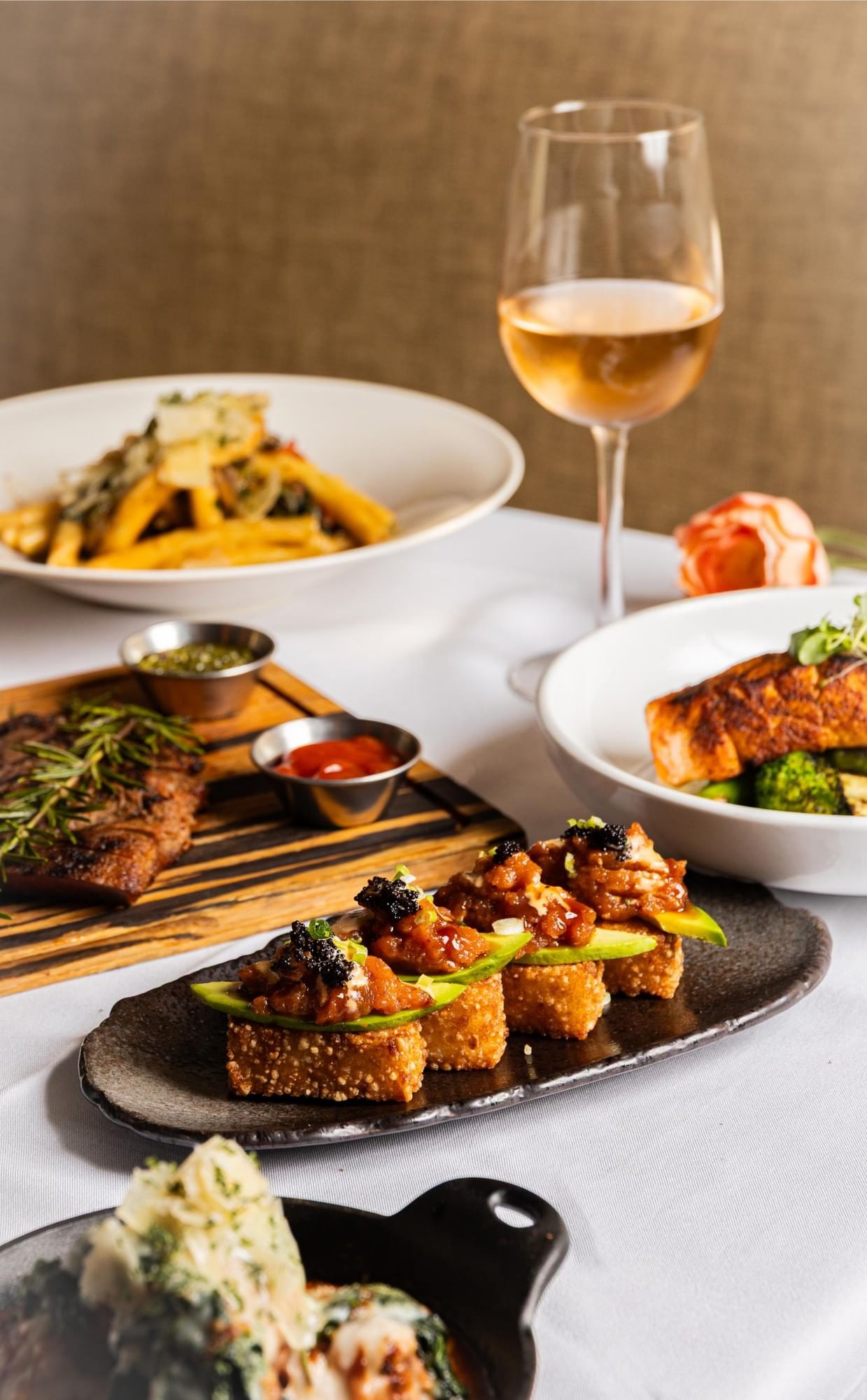 A table set with various dishes of food and a glass of wine.