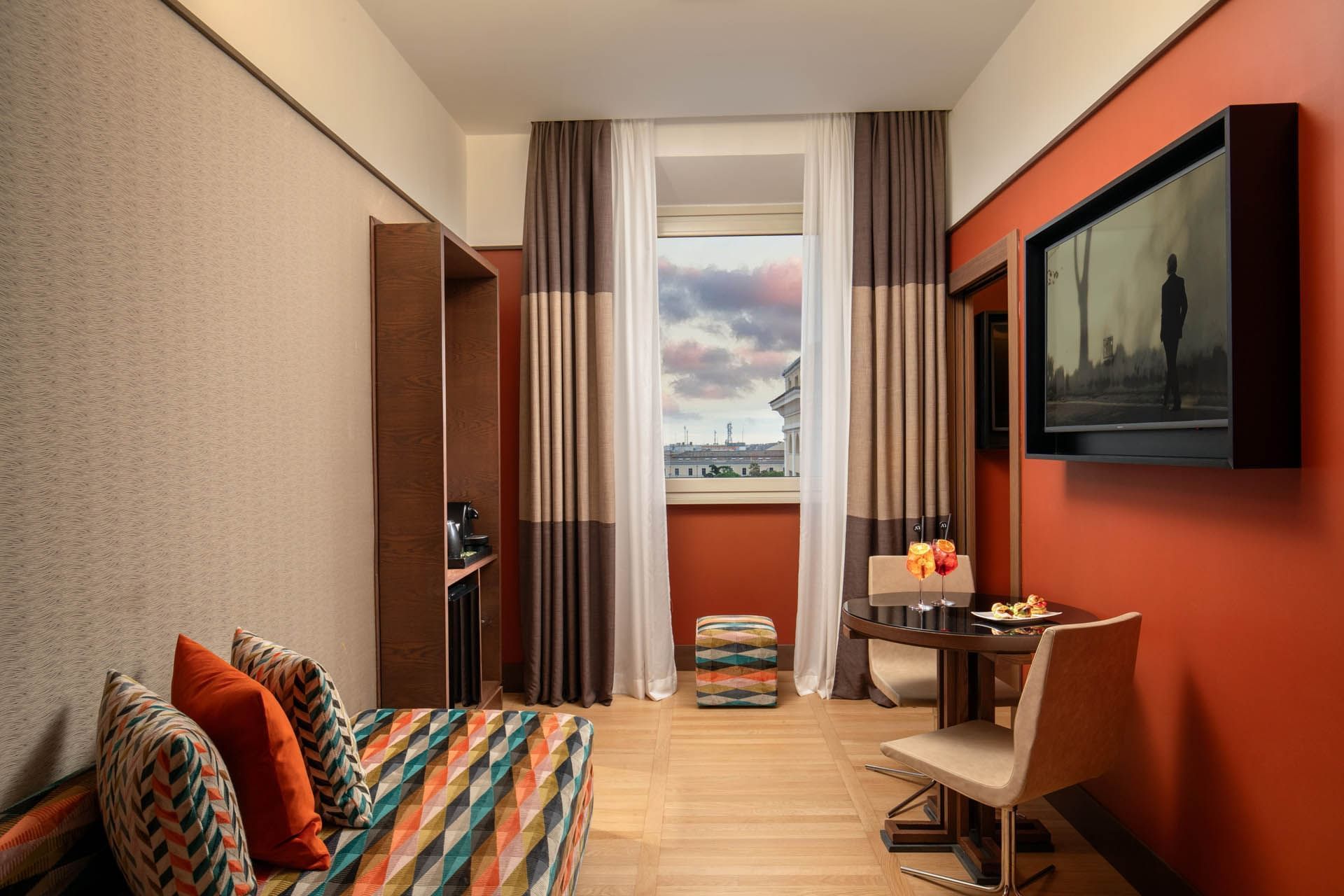 Stylish Junior Suite at The Independent with bright decor, large windows, a dining table, and refreshments