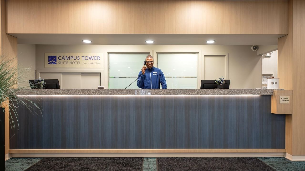 Man talking on phone at Campus Tower Suite Hotel reception desk.