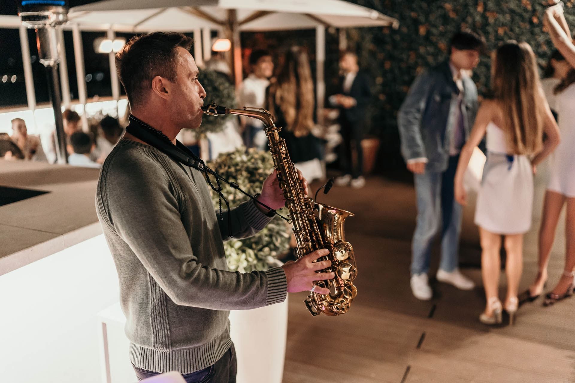 A musician plays saxophone at Terrazza Cielo as guests dance and enjoy the mood under soft lights at AG Hotels