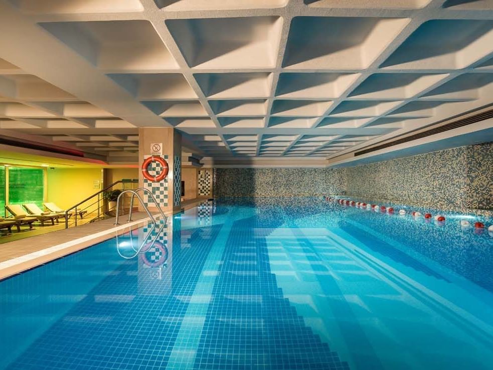 Titanic Port Bakırköy’deki kapalı havuz alanında, şık şezlonglar ve modern dokunuşlar sunan geometrik tavan eşliğinde huzur dolu bir spa deneyimi yaşayın.
