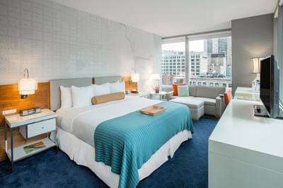 Bed, nightstand, sofa & TV in Corner King Room at Kinzie Hotel