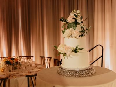 Wedding cake with white roses on table at Carriage House Hotel