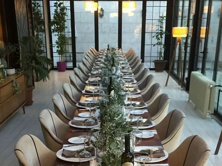 Banquet table with wine by chairs surrounding a floral centerpiece in Maple Tree Restaurant at Warwick Ankara