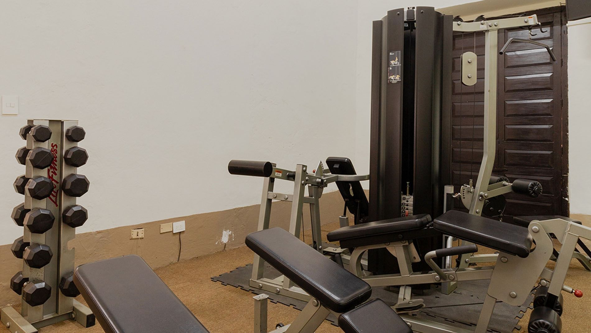 Workout room with Life Fitness dumbbells and various silver weight-lifting machines at Quinta Real Puebla
