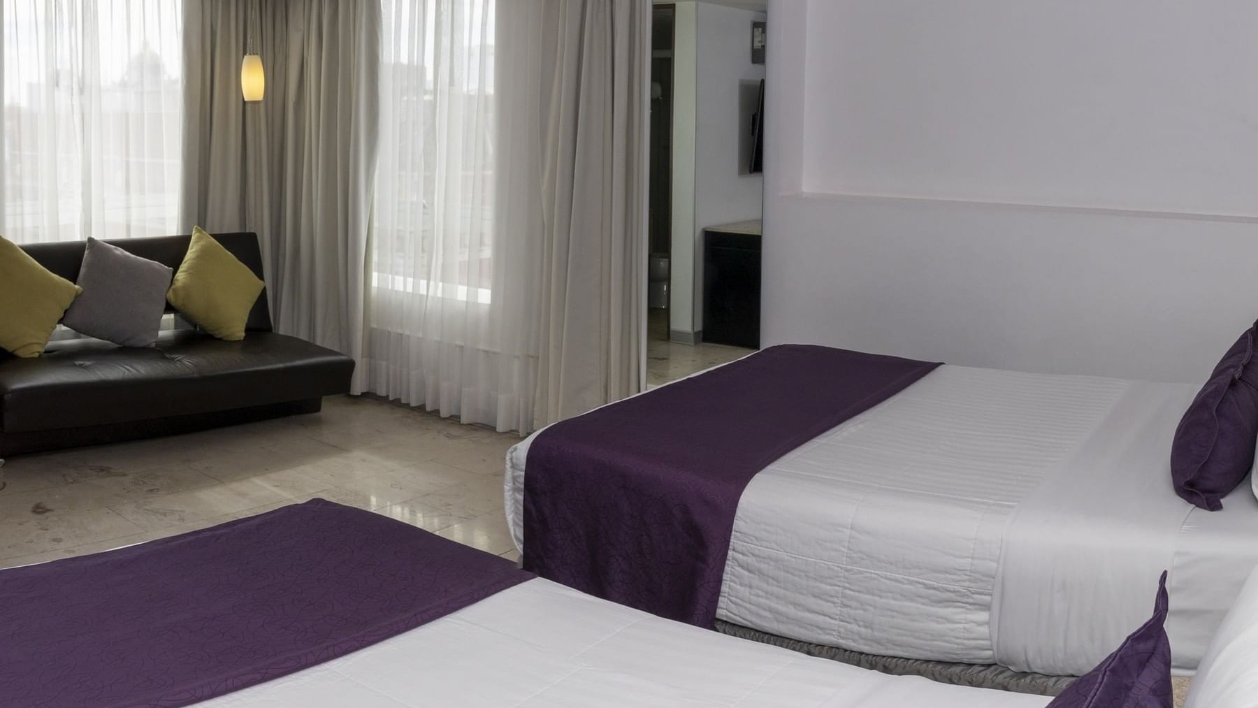 Two beds & comfy sofa with pillows in a room at Gamma Puebla Senorial Centro