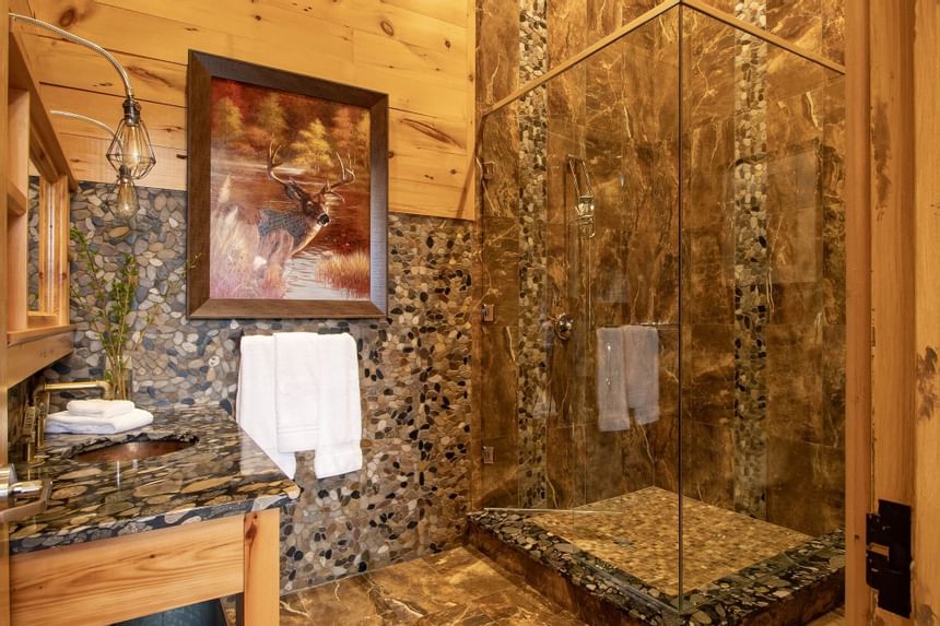 glass walk in stone shower in log cabin suite
