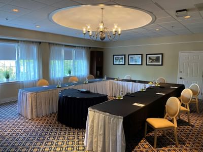 Talcott meeting room with U-shaped tables covered in black and white tablecloths under a chandelier at The Simsbury Inn