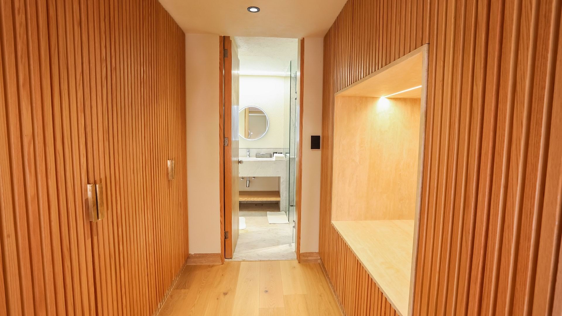 Wooden hallway leading to a bathroom with a mirror at Camino Real Polanco Mexico in Ciudad de Mexico.