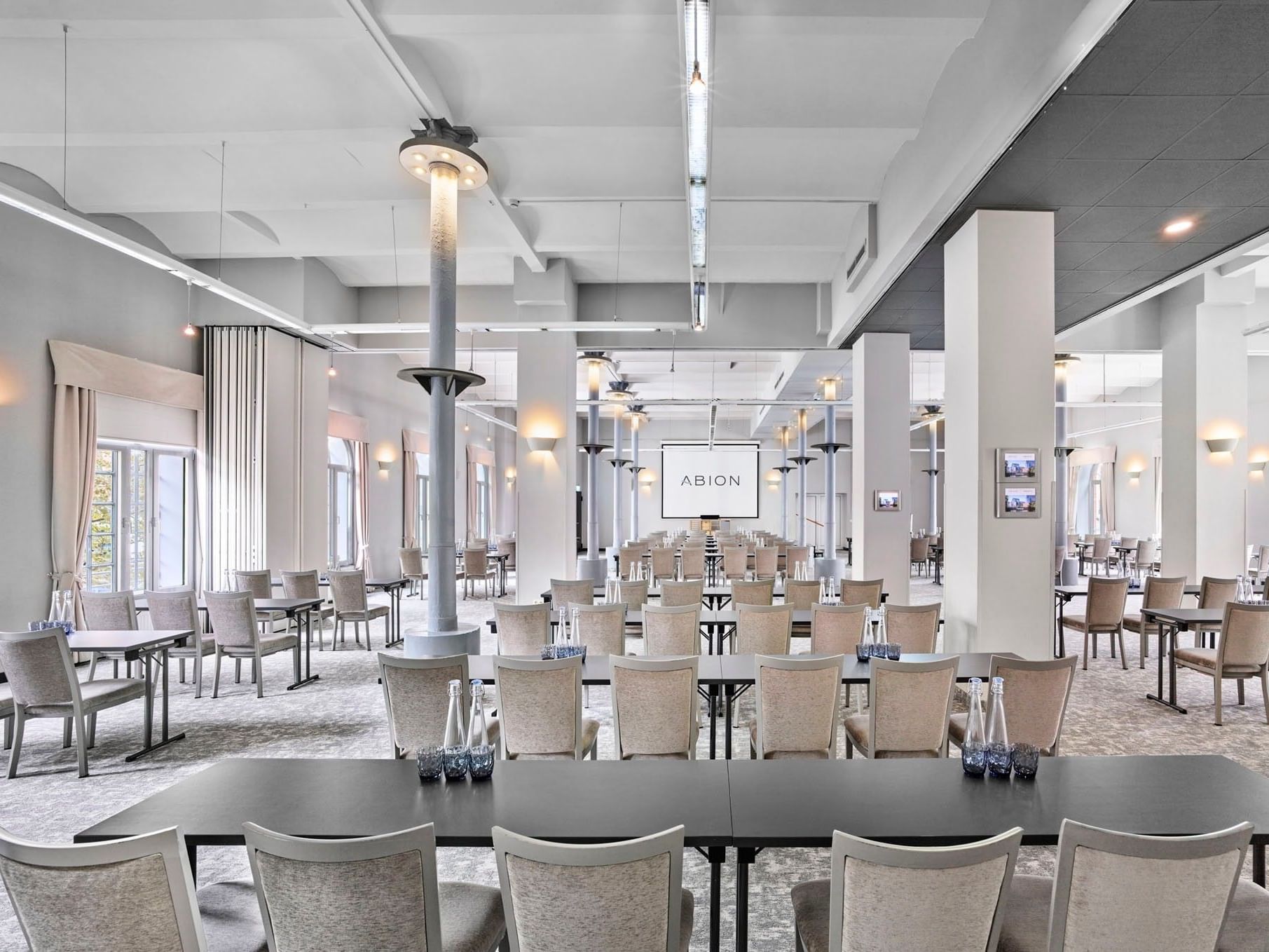A spacious event room with tables and chairs at Abion Spreebogen Waterside Hotel Berlin.