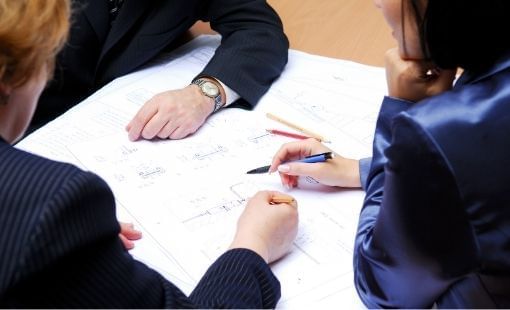 Three professionals discussing documents on a table at Sunway Hotel Big Box