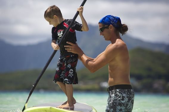 Man teaching little boy to surf on a sunny day at Paradise Bay Resort