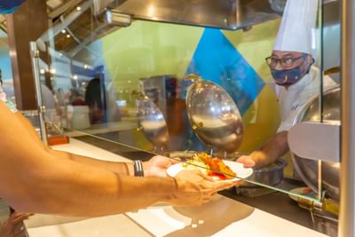 A chef serves a fresh meal to guest at Fiesta Resort