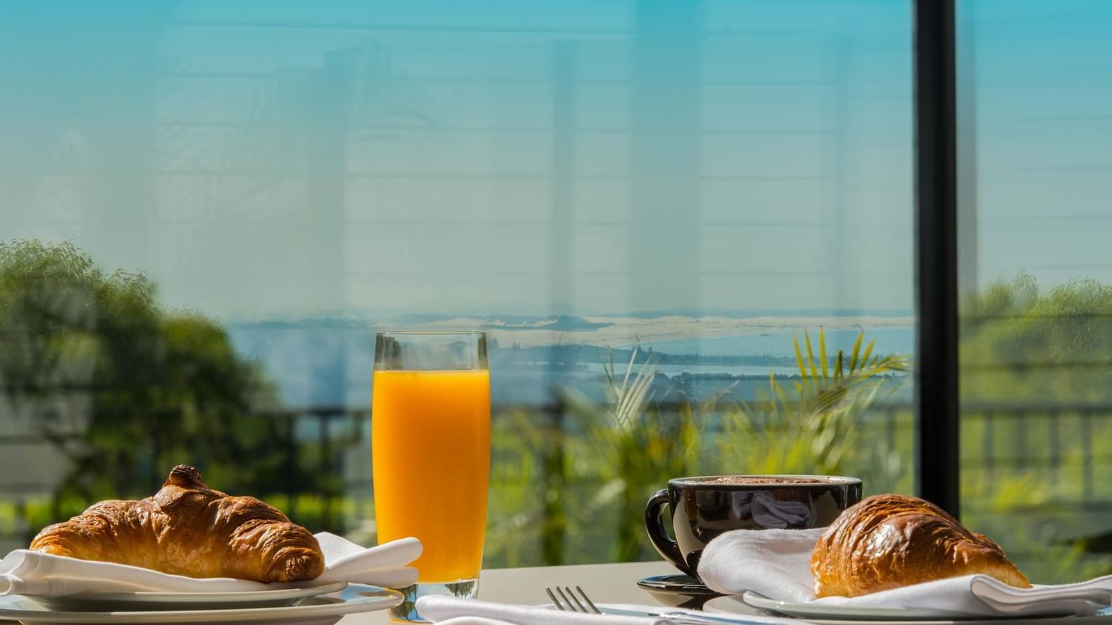 Breakfast croissants, fresh juice and coffee served on a table outdoors overlooking the city view at Mercure Charlestown