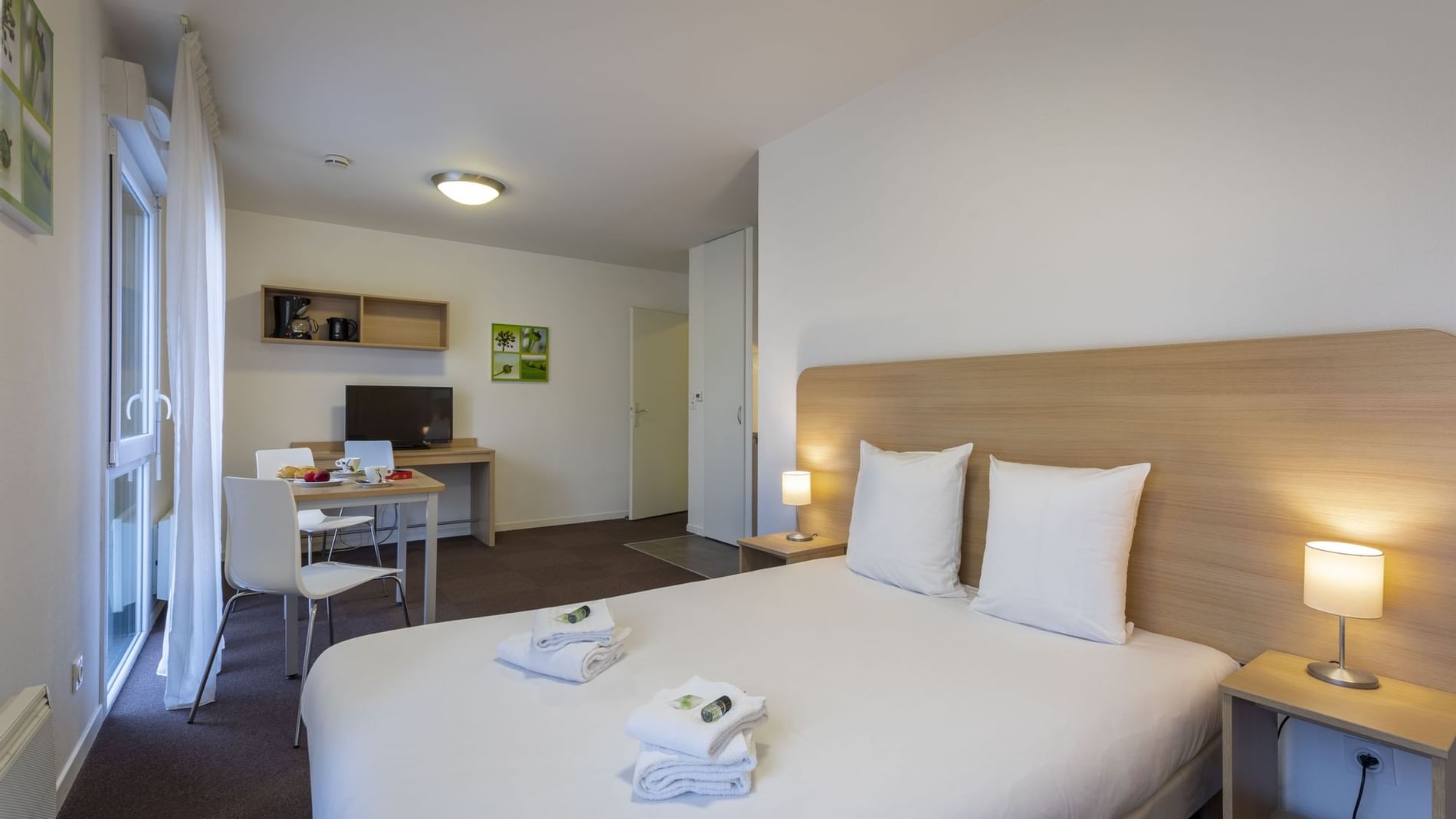 Folded towels on a bed with white bedding at Originals Hotels