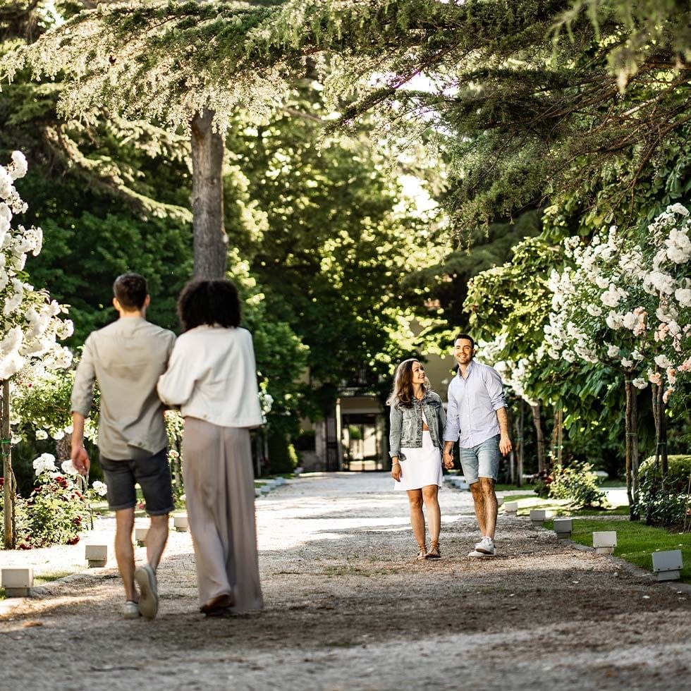 Zwei Paare genießen Frühlingserwachen am Meer auf einem idyllischen Gartenweg.