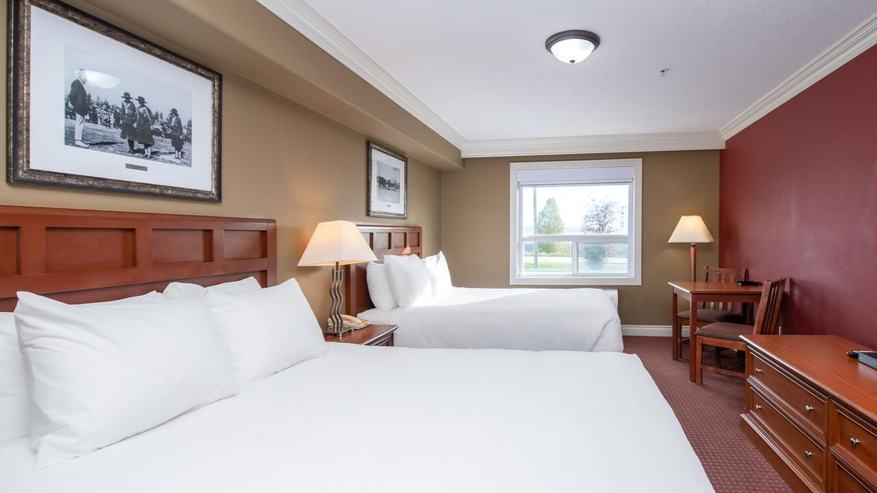 Double guest room with white linens, wooden furniture, and vintage photographs at Coast Edson Hotel