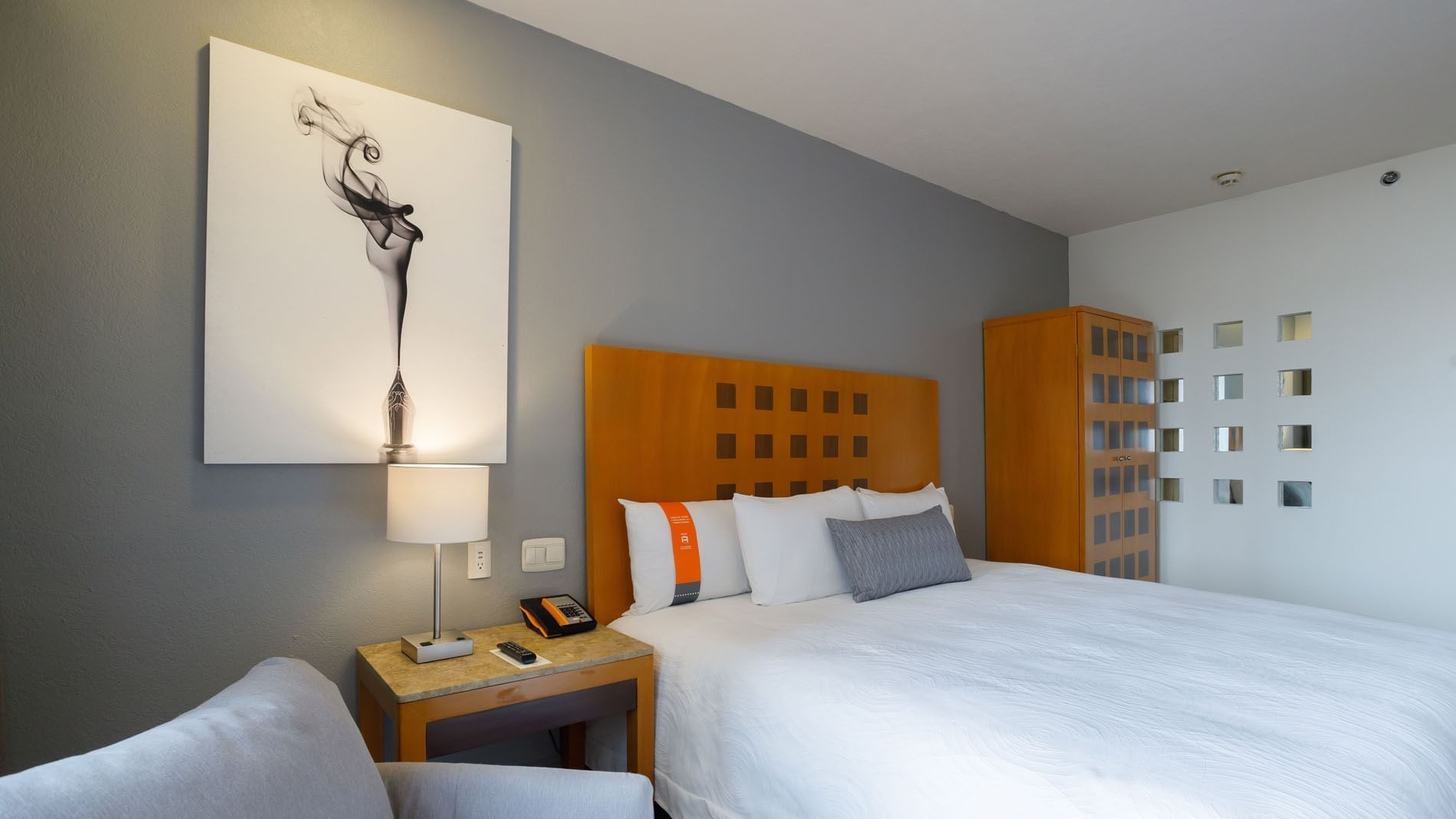 1 Double Deluxe Handicap Accessible room with grey walls, artistic wall decor, and a warm bedside lamp at Real Inn Torreon