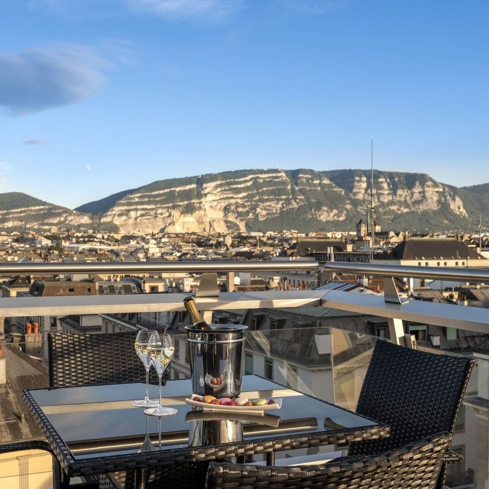 Rooftop terrace with a glass table, nestled among chairs and a wine bucket in Penthouse Terrace Room at Warwick Geneva
