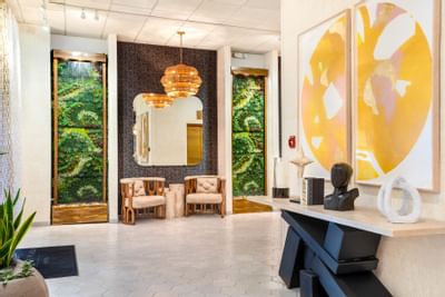 Stylish lobby at The Riverwalk Plaza Hotel with modern decor, a chandelier, and an accent wall featuring green plant designs
