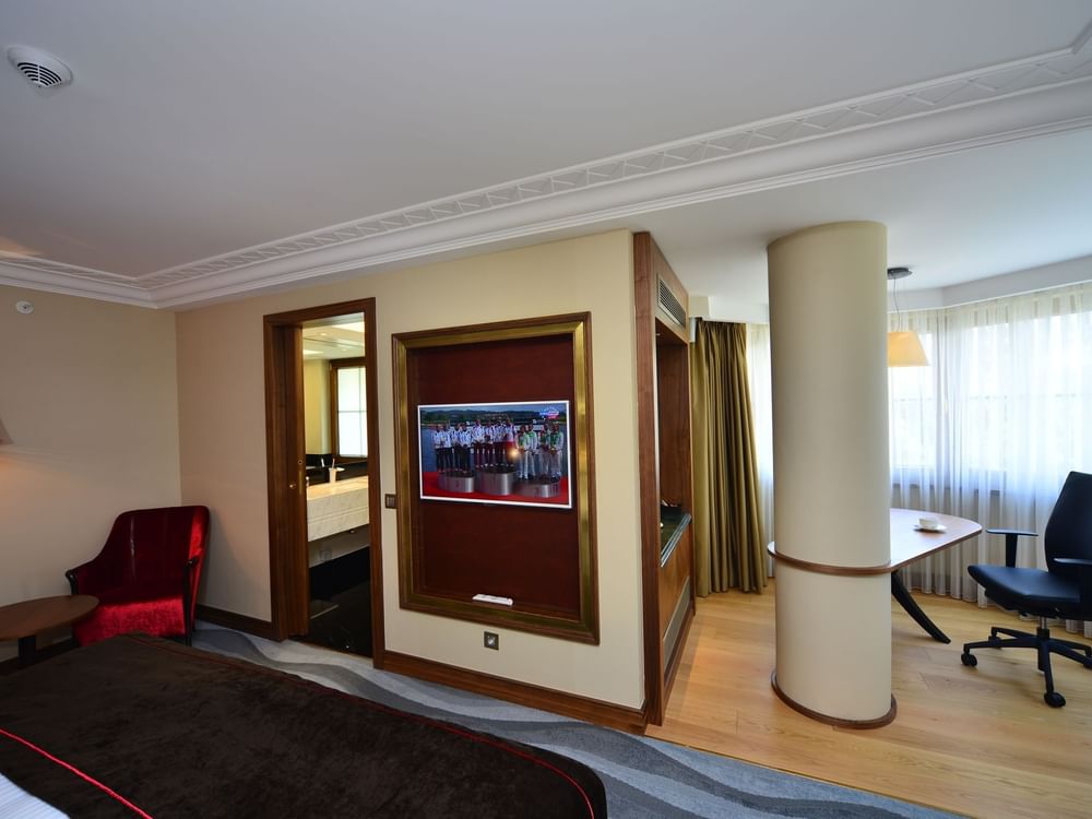 Office chair by a desk surrounding a pillar under a wall-mounted TV in Executive Room at Warwick Ankara