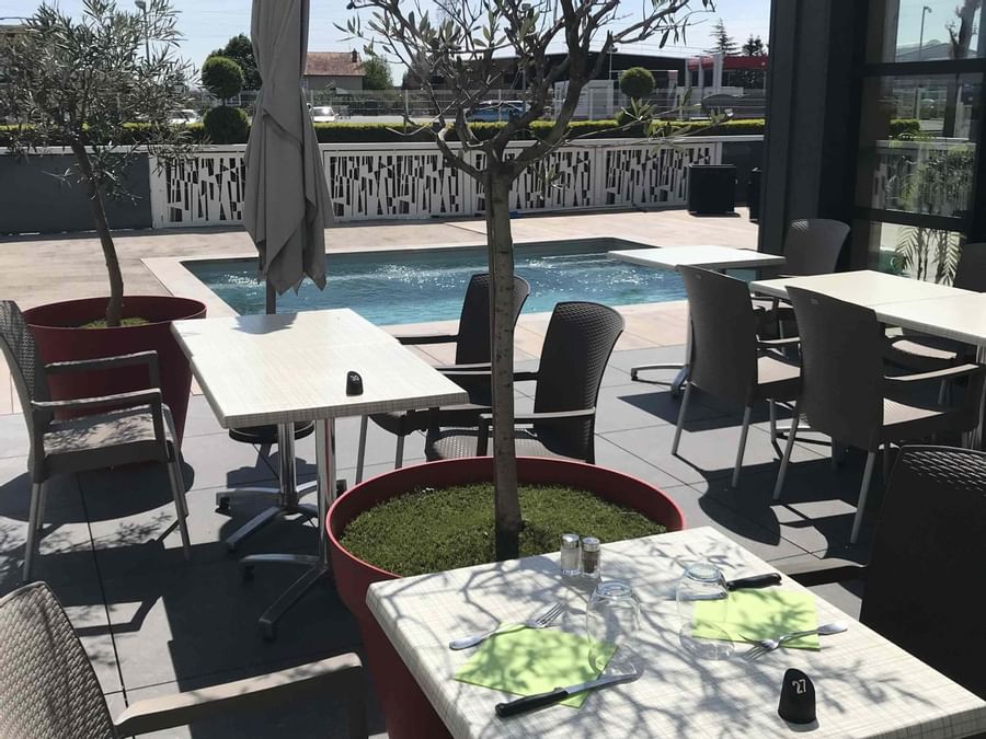An outdoor dining area by the pool at Hotel Helios